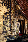 Wat Xieng Thong temple in Luang Prabang, Laos. The facade of the sim decorated with gold stencilling on a black lacquer background. 